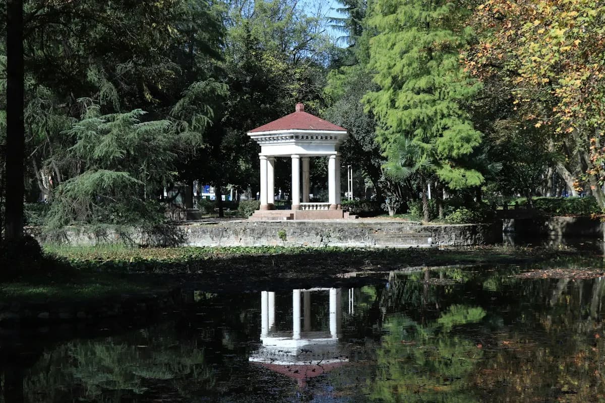 White garden pavilion reflected in a pond